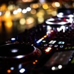 a close up of a dj controller with blurry lights in the background