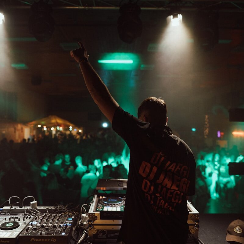 a man holding a microphone in front of a dj booth
