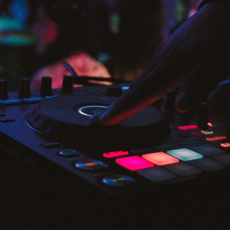 person playing dj controller in a dark room